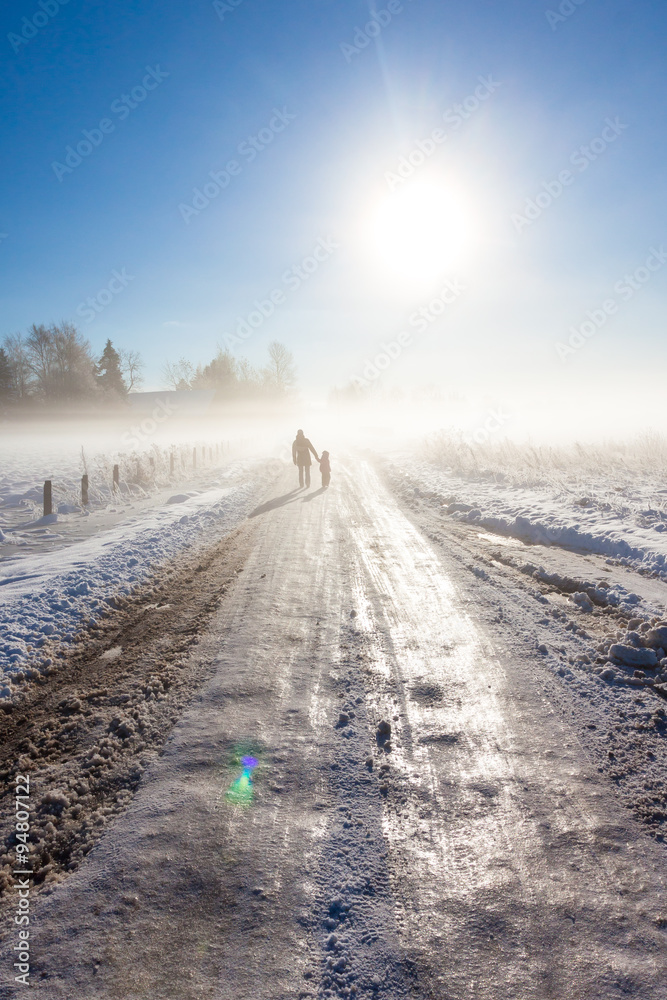 Fototapeta premium Mother and child on foggy snow road