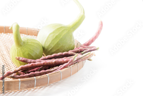 bottle gourd fruit and purple cowpea in basket isolated photo