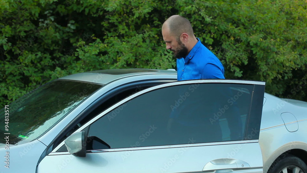 Young man approaching and entering grey passenger car Young man approaching and entering grey passenger car
