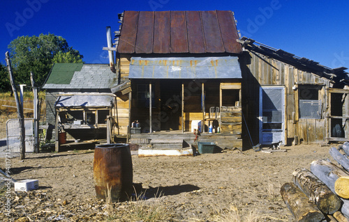 Fényképezés Old ramshackle dwelling with oil drum in dirt yard