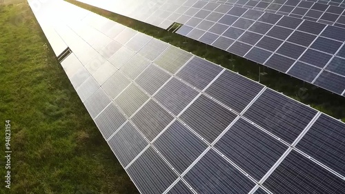 Aerial shot of solar farm at sunset moving forwards, medium shot.