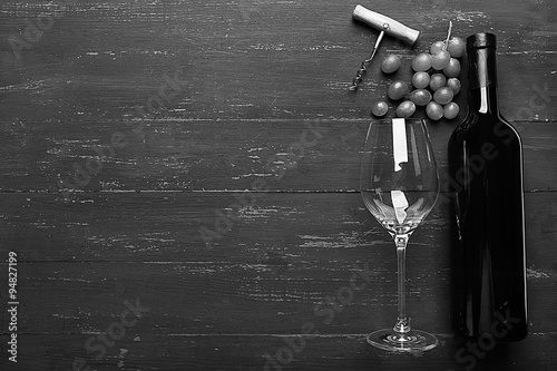 Bottle of wine and grape on wooden table,  black and white retro stylization