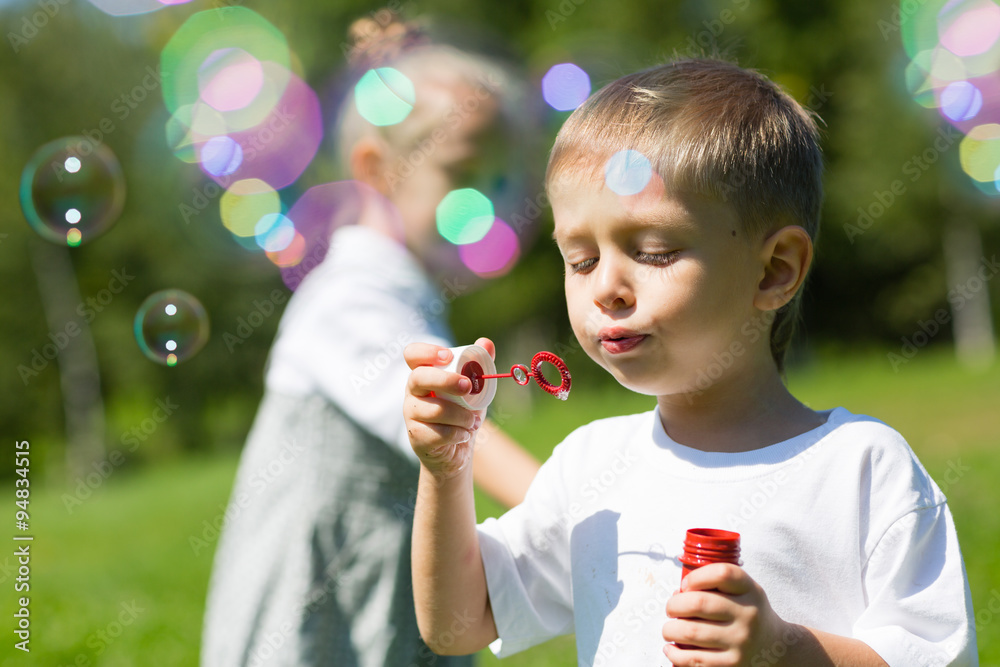 Happy little children blow soap bubbles
