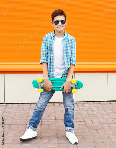 Stylish teenager boy wearing a shirt, sunglasses and skateboard