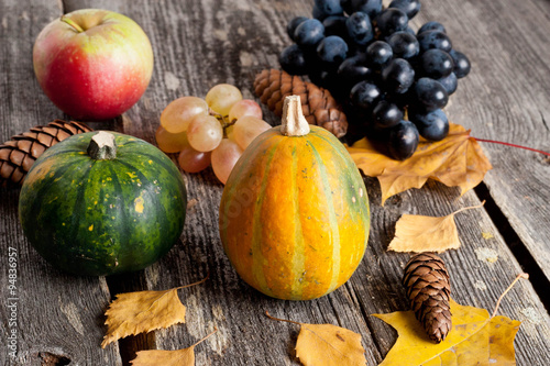seasonal pumpkin and grapes with autumn leaves, closeup, vertica