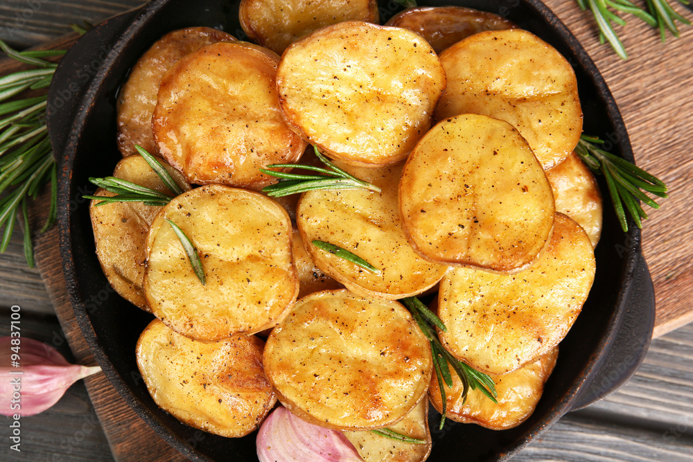 Delicious baked potato with rosemary in frying pan on table close up Delicious baked potato with rosemary in frying pan on table close up