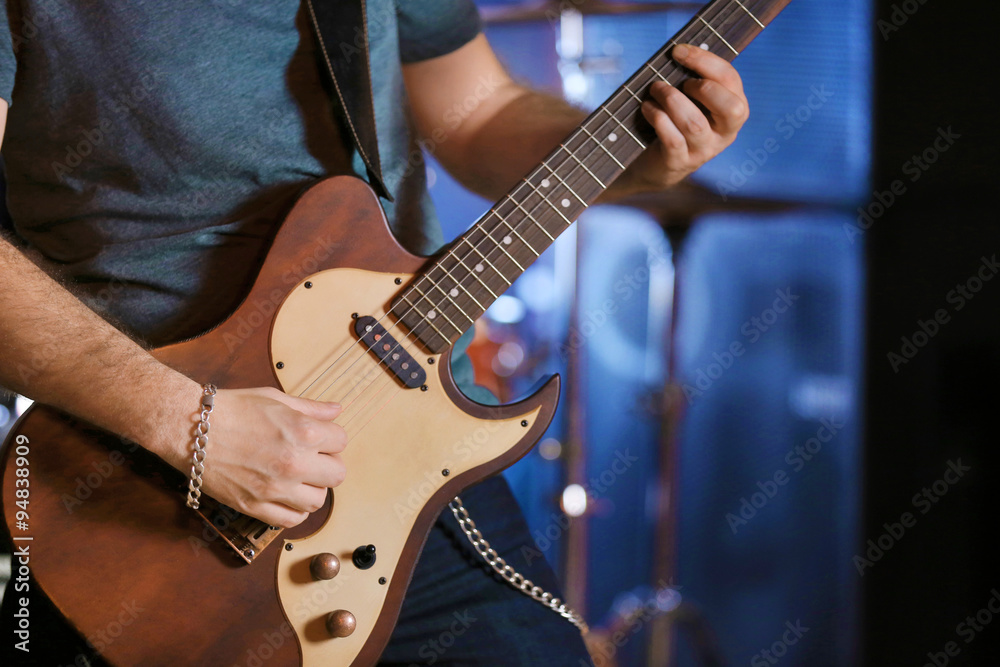 Fototapeta premium Young man playing on electric guitar close up