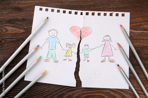 Torn apart drawing of a family on wooden background