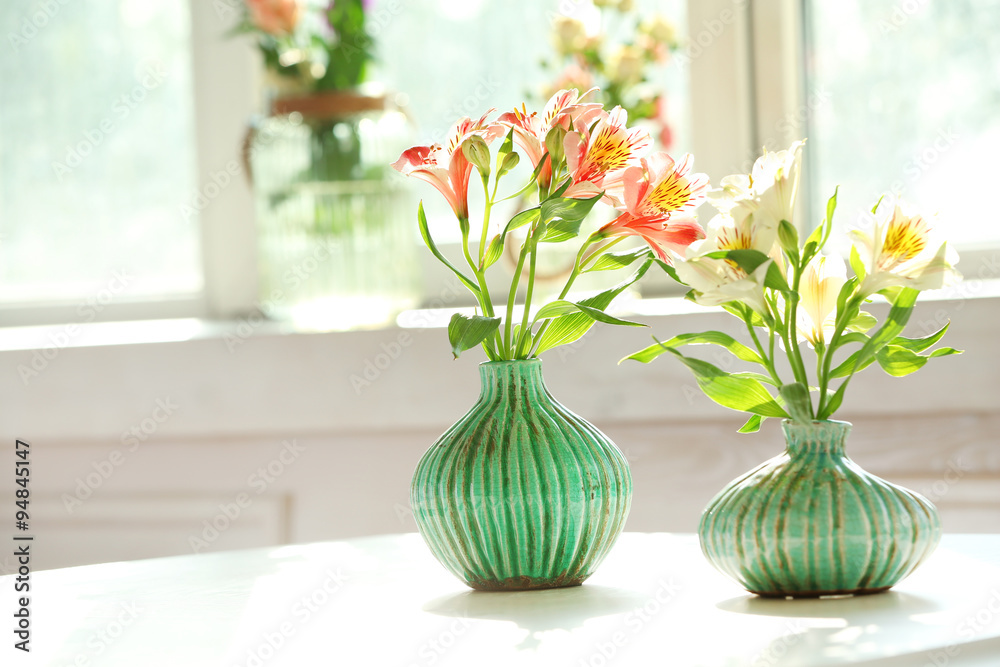 Beautiful Alstroemeria flowers in aquamarine vases on window background Beautiful Alstroemeria flowers in aquamarine vases on window background