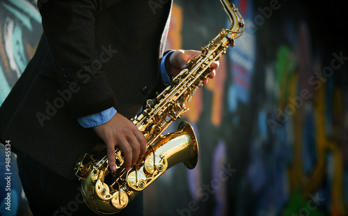 Photography Young man with saxophone outside near the old painted wall