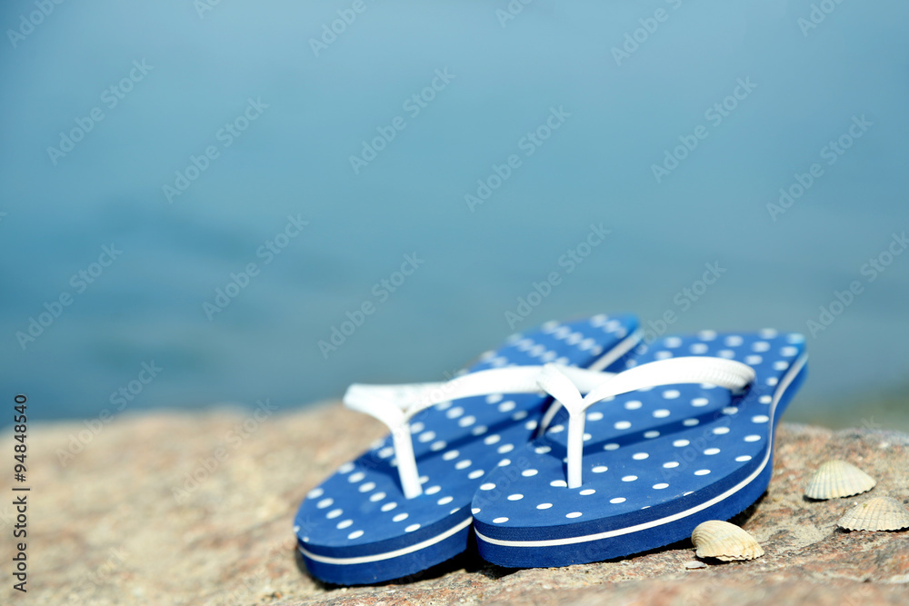 Obraz premium Bright flip-flops on stone, nature background