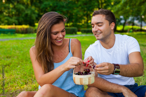 Couple eating cherries from basket in park