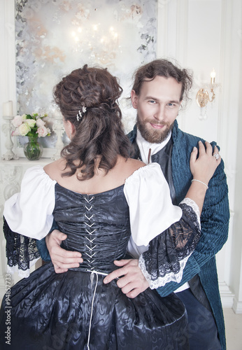 Obraz na plátně Handsome man untying corset of woman in medieval dress