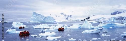 Panoramic view of ecological tourists in inflatable Zodiac boat with glaciers and icebergs in Paradise Harbor, Antarctica