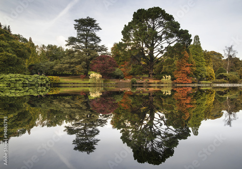Beautiful Autumn Fall forest landscape reflected in calm lake photo