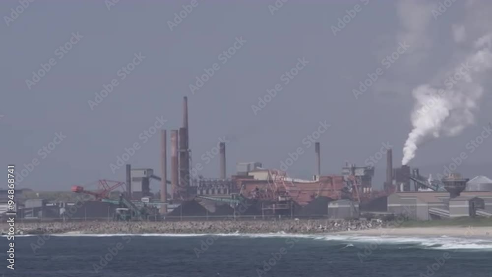 Panning shot of large factory on shoreline. Panning shot of large factory on shoreline.