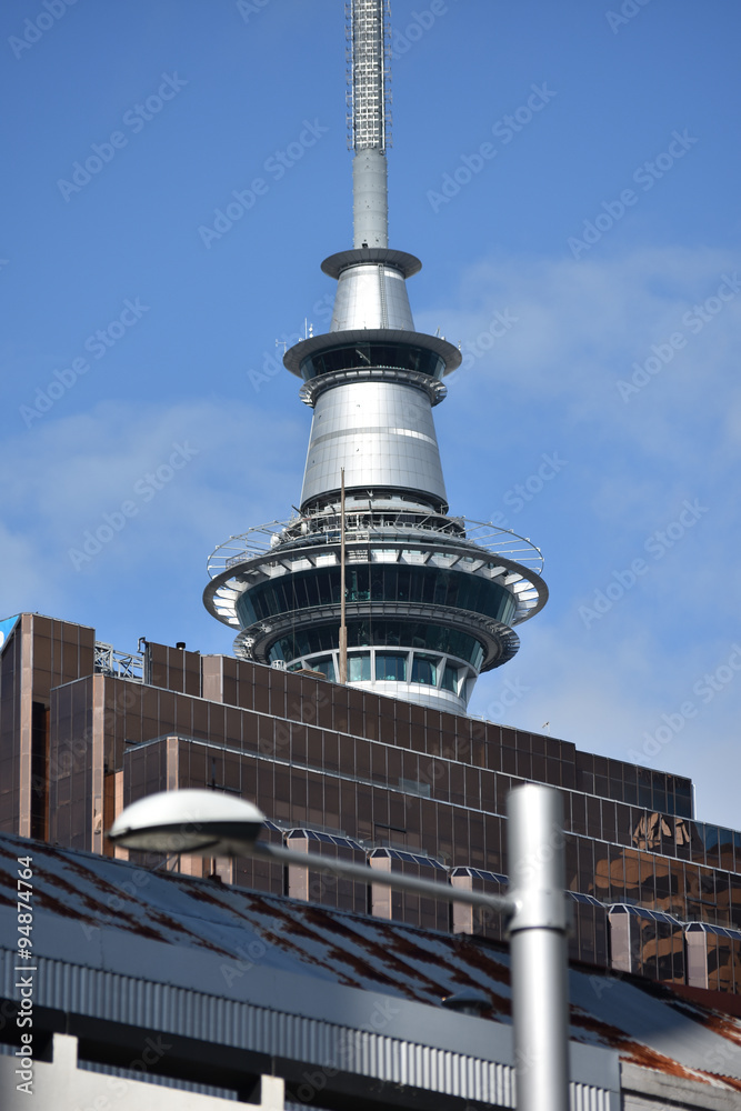 Sky Tower top hiding behind other tall buildings in Auckland CBD.