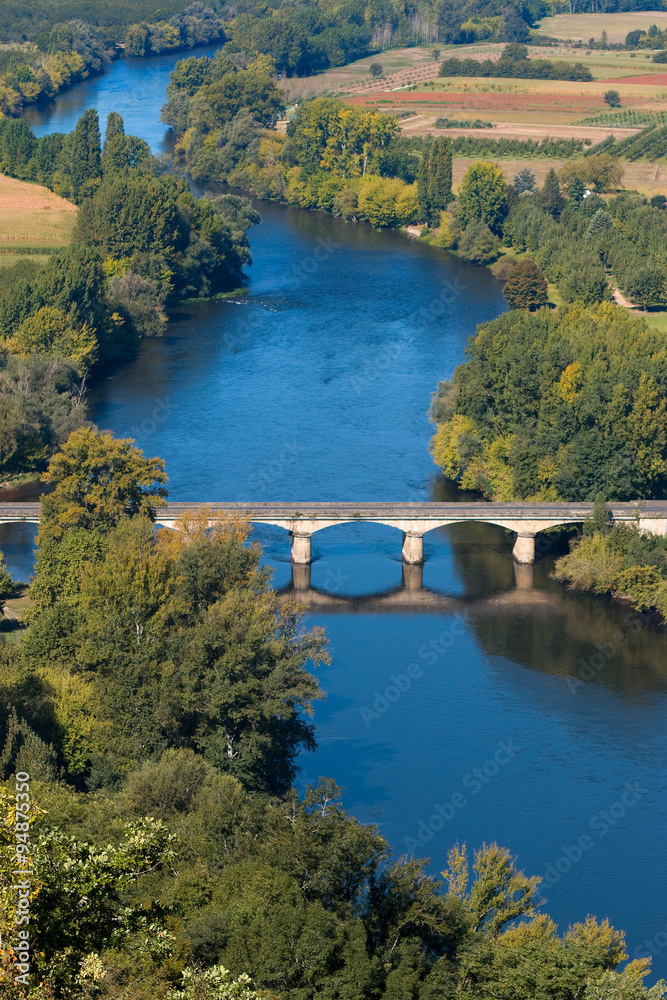 Obraz premium View over the Dordogne river seen from Domme village. The bridge over the river in Domme city. Medieval bridge crossing blue river in Perigord region. Bastide town in Dordogne, France.
