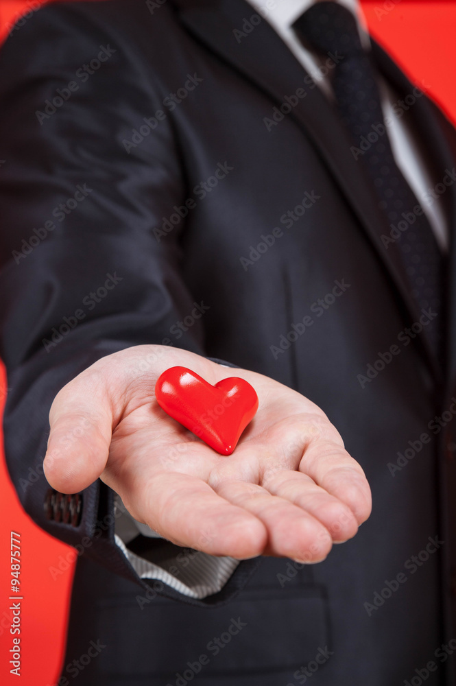 Young man holding a red heart on the palm Young man holding a red heart on the palm
