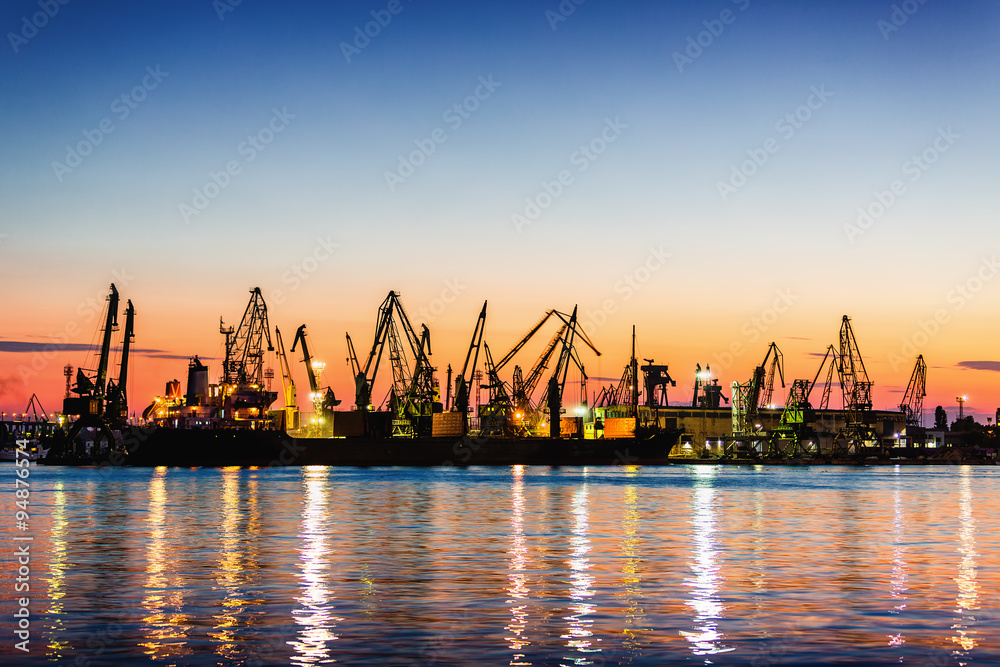 Sea commercial port and working Industrial cranes. Cargo freight ship in sea harbour at sunset. Logistic and shipping. Small electric blender