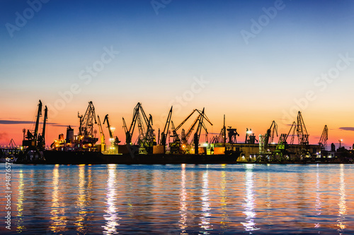 Sea commercial port and working Industrial cranes. Cargo freight ship in sea harbour at sunset. Logistic and shipping. Small electric blender