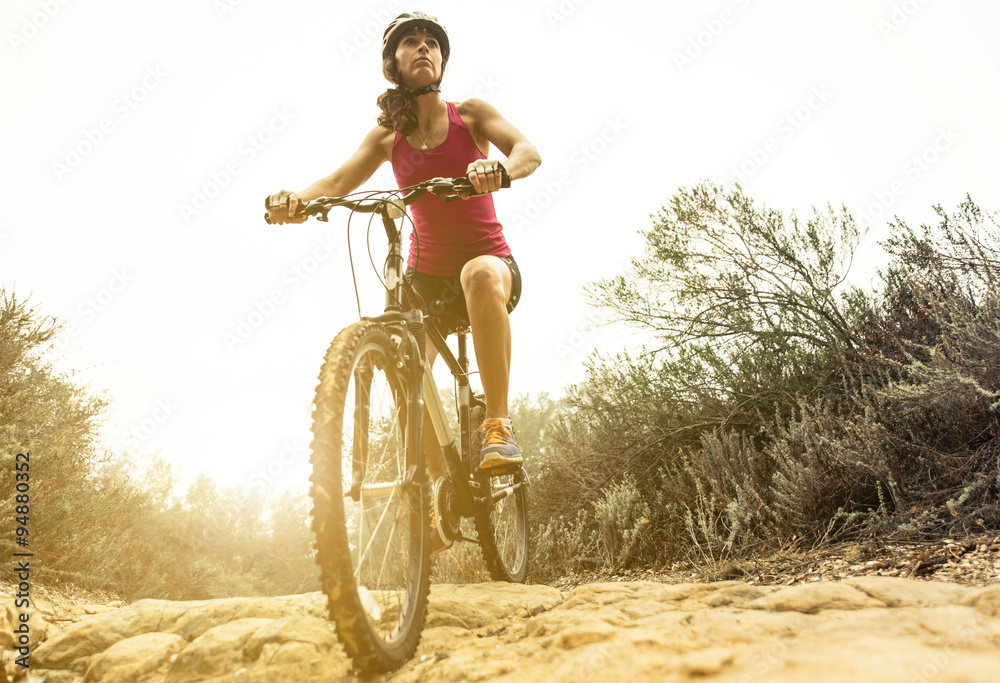 Obraz premium Young woman making downhill with her mountain bike