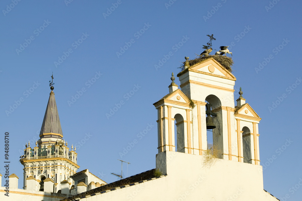 Storks nest on white cathedral tower with beautiful sunlight in village of Southern Spain off highway A49 west of Sevilla