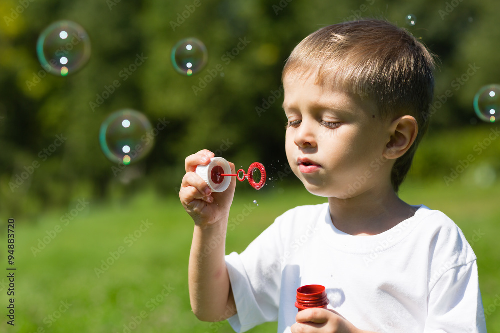Cute boy blowing soap bubbles