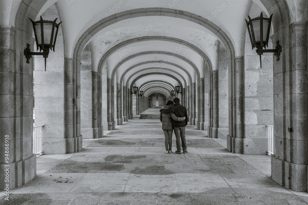 Black and white picture of a couple in a symmetrical corridor