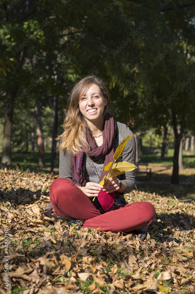 Happy brunette girl sitting among yellow autumn leaves Happy brunette girl sitting among yellow autumn leaves