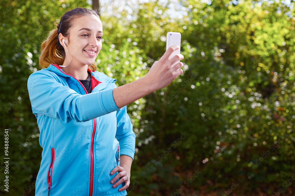 Young Sporty Woman Taking a Selfie at Park. She is Looking at Sm Young Sporty Woman Taking a Selfie at Park. She is Looking at Sm