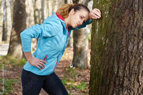 Young female runner is having break and listening to music durin