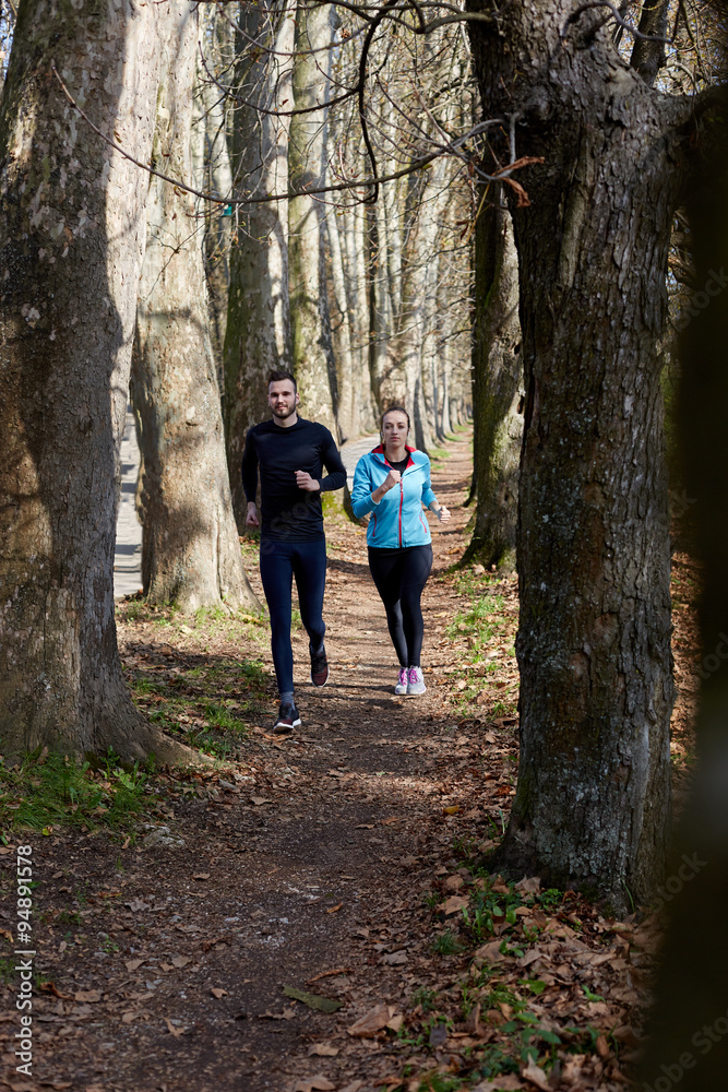 Young couple running together in park - fall nature