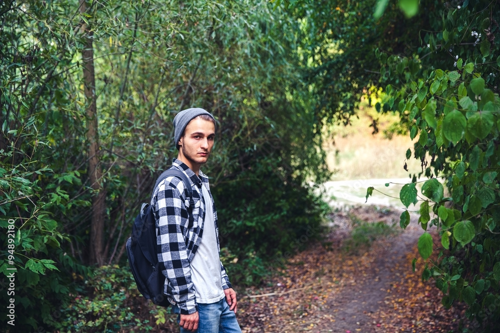 Portrait of young handsome man with backpack wanderer walk in the woods