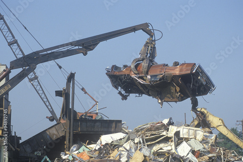 A wrecking crane lowering a demolished automobile onto a pile of junk, Atlanta, Georgia