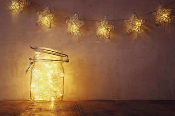 low key and vintage filtered image of fairy lights in mason jar with. selective focus. glitter overlay
