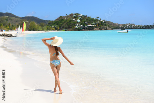 Beach travel woman bikini wearing sun hat walking