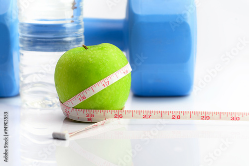 Measuring tape wrapped around a green apple as a symbol of diet