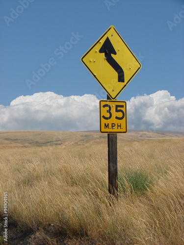 Traffic sign with bullet holes in wheat field