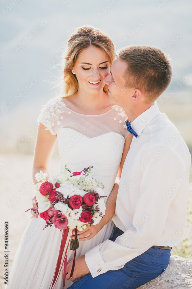 Young happy just married couple posing on the top of the mountain. Wedding day Young happy just married couple posing on the top of the mountain. Wedding day