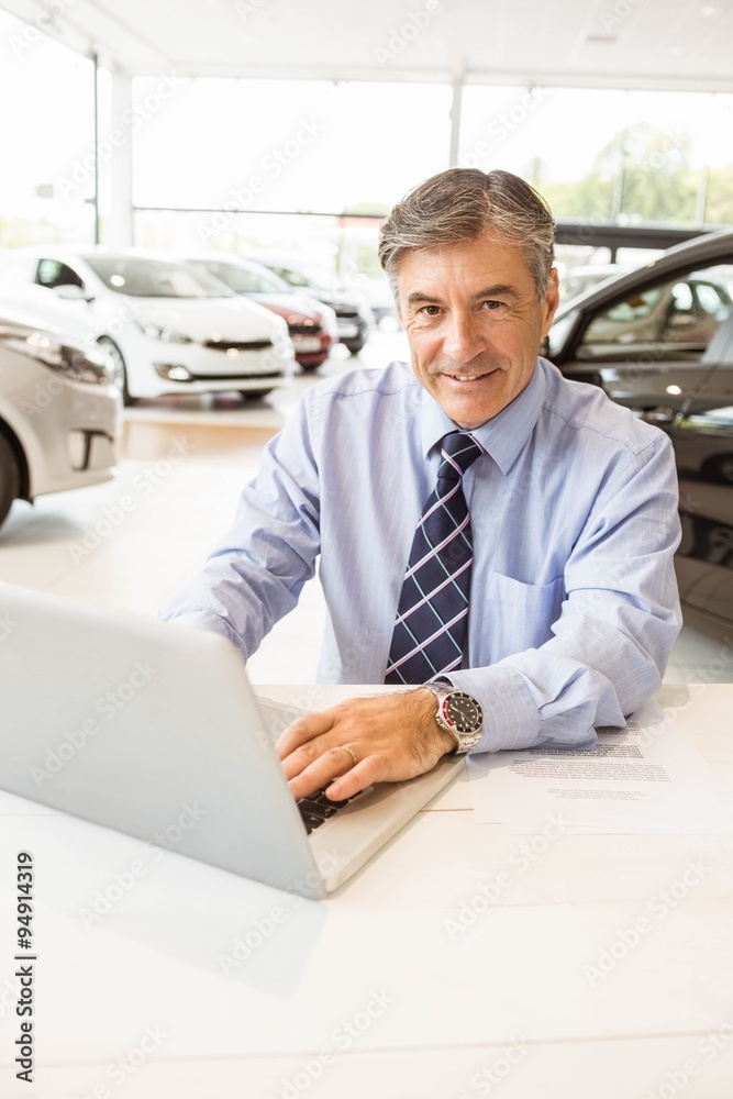 Fototapeta premium Smiling salesman behind his desk