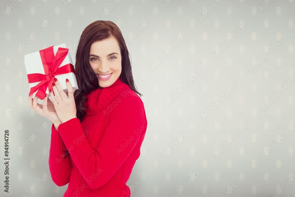 Smiling brunette in red jumper hat showing a gift Smiling brunette in red jumper hat showing a gift