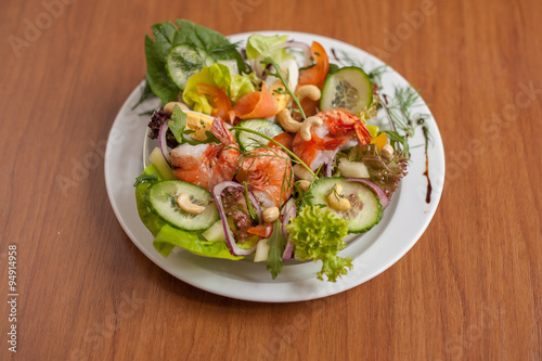 Colorful salad with shrimps on wooden table. Close up.