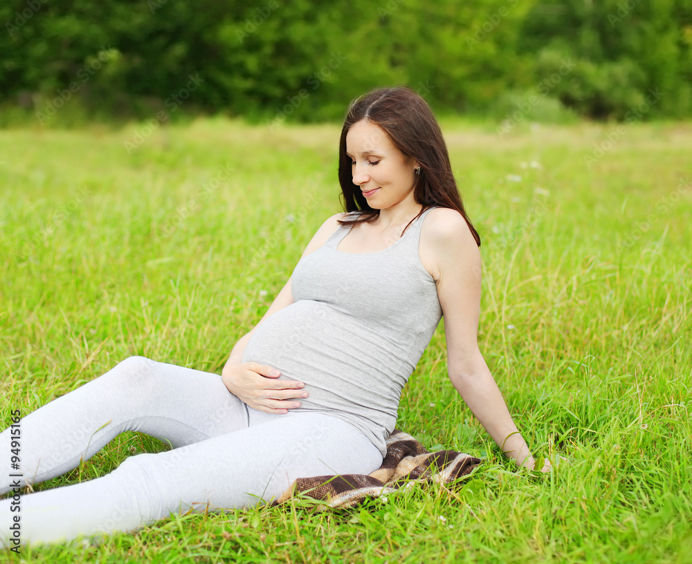 Happy smiling pregnant woman on grass in summer day Happy smiling pregnant woman on grass in summer day