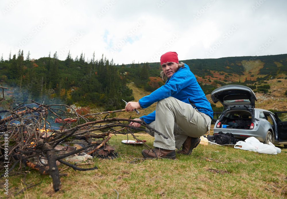 hiking man prepare tasty sausages on campfire hiking man prepare tasty sausages on campfire
