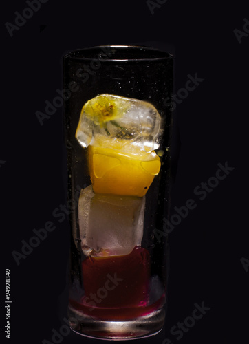 Glass of colored ice cubes isolated on black