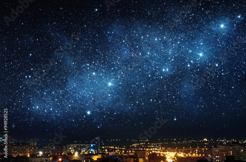 City landscape at nigh with sky filled with stars. Elements of this image furnished by NASA. © Tryfonov