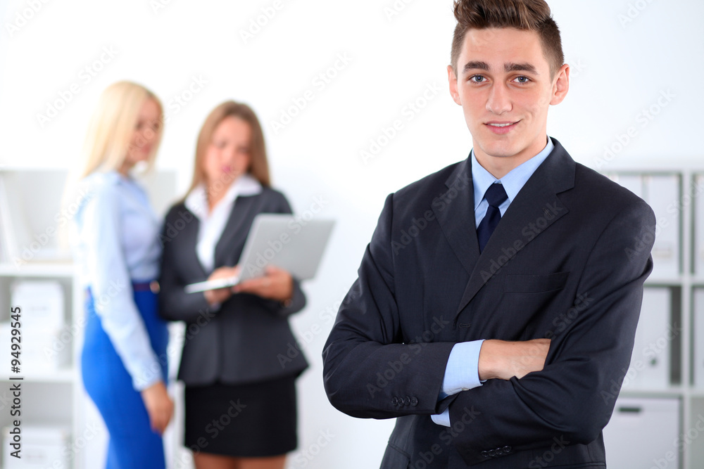 Cheerful business man in office with colleagues in the background, sturt-up team Cheerful business man in office with colleagues in the background, sturt-up team