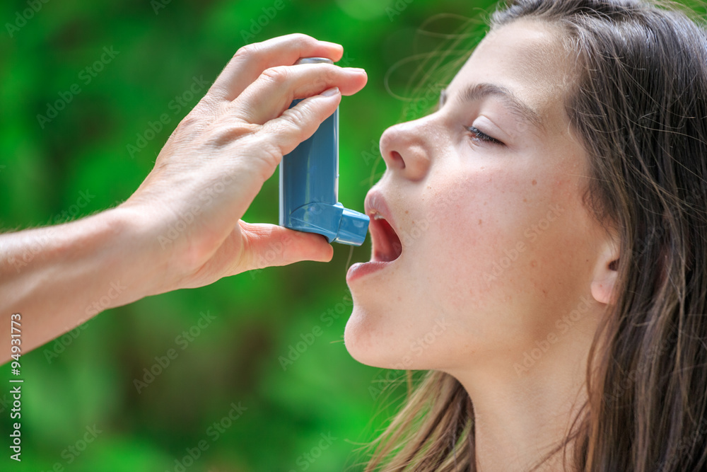 Portrait of a girl using inhaler for asthma from his mothers hand Portrait of a girl using inhaler for asthma from his mothers hand