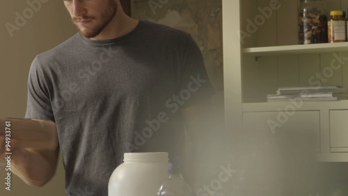 Slow motion clip of a young man making a protein shake at home photo